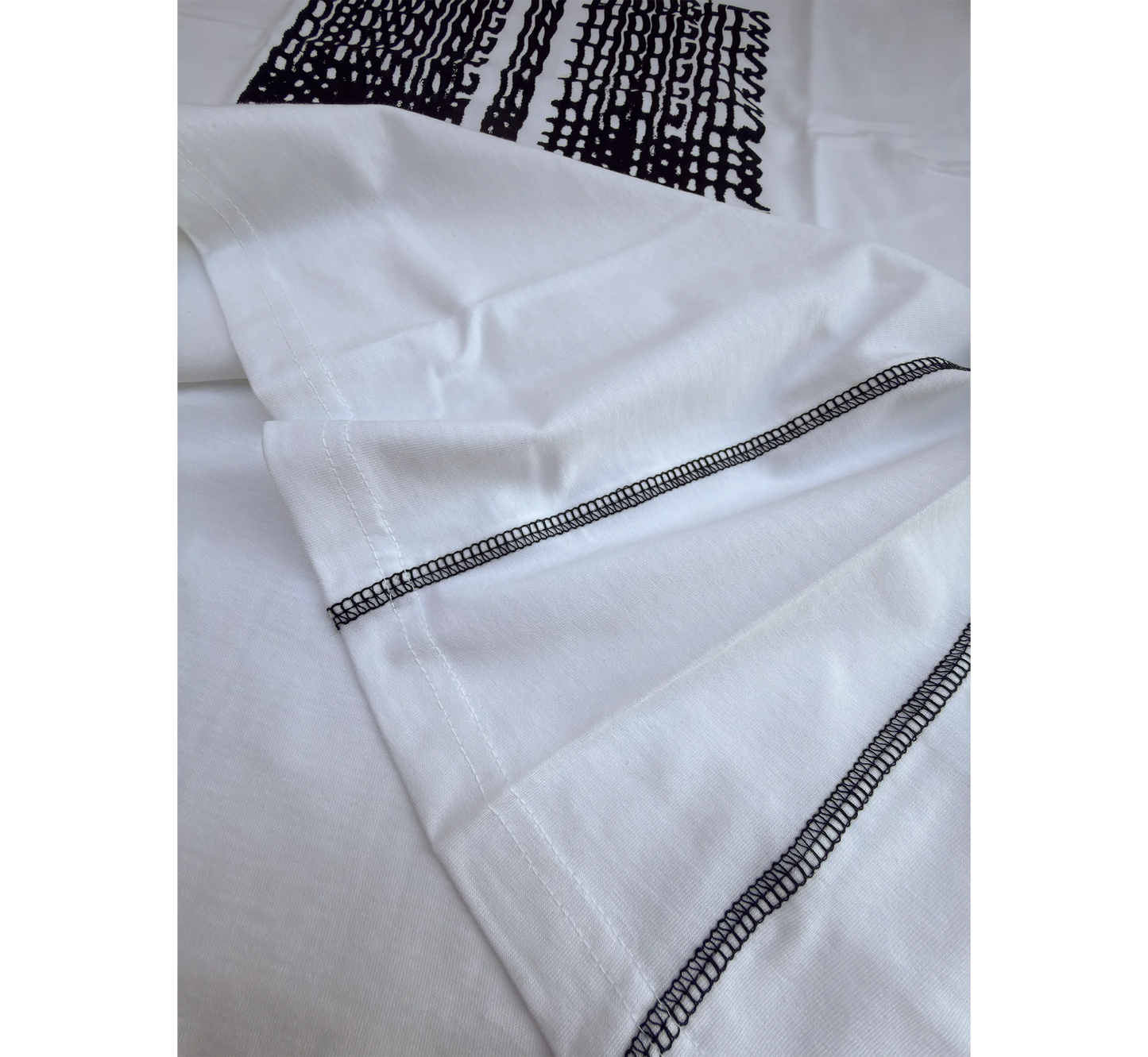 Close-up of white t-shirt side seams and black graphic design