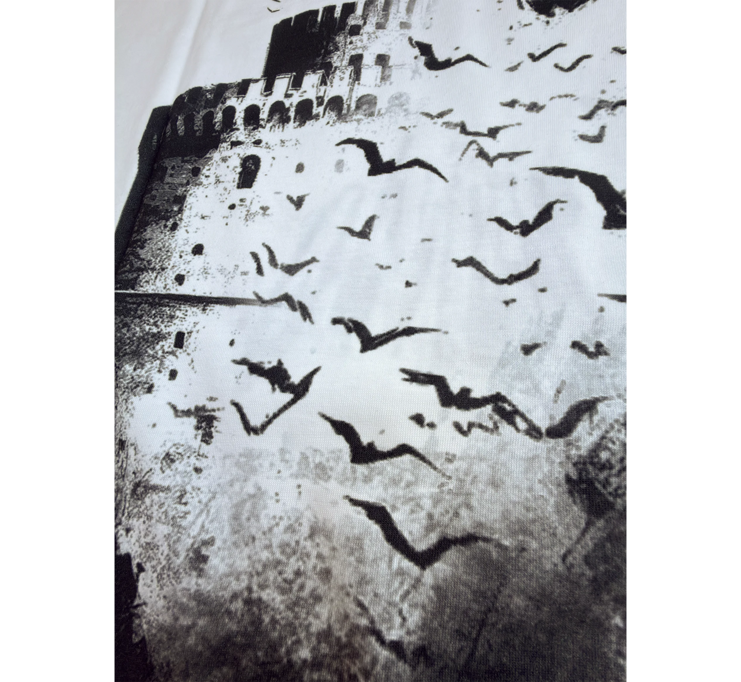 Black and white pattern of birds flying over a the white tower of Thessaloniki.