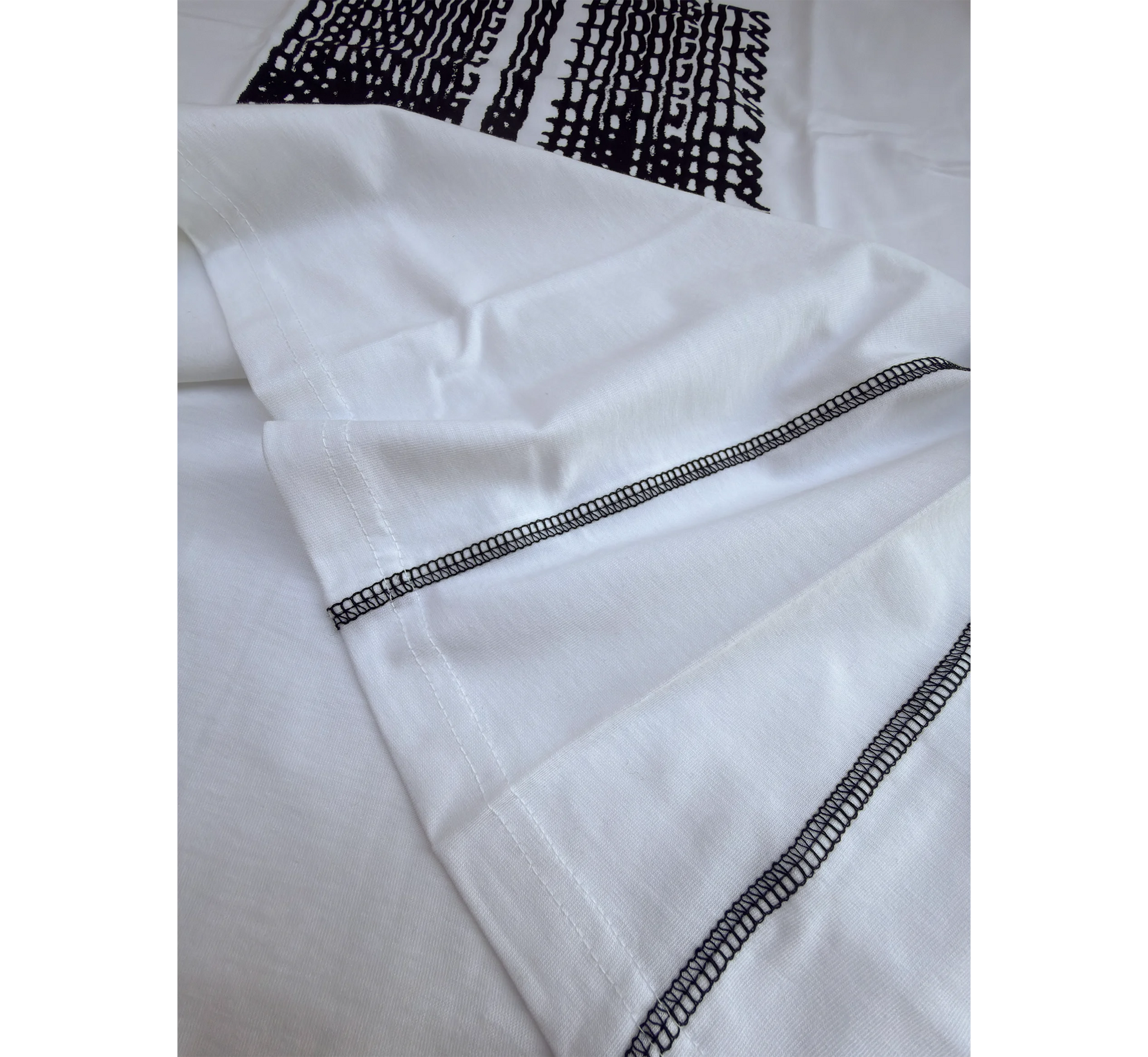 Close-up of white t-shirt side seams and black graphic design