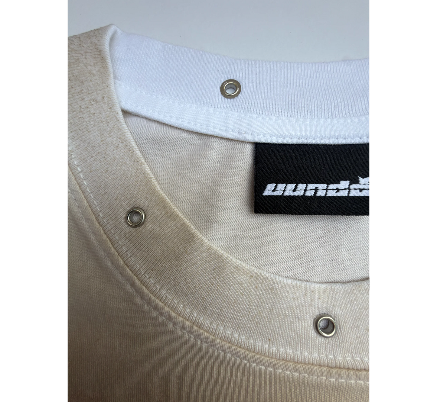 Close-up of a beige and white t-shirt with a white collar and 'uundo' brand label.